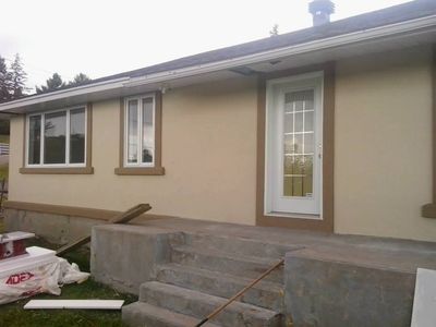 Entrada principal tras la obra, acabado acrílico crema con marcos marrones.